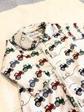 Bobbie's Shoppe white footed pajamas with a repeating print of red, blue, and green tractors. Scalloped collar.